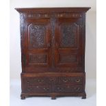 An 18th century joined oak livery cupboard, having twin blind carved panelled doors, opening to