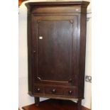 An early 19th century provincial oak and mahogany crossbanded single door corner cupboard, having