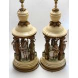 A pair of large cream painted Toleware table lamps, each surmounted by four bisque porcelain figures