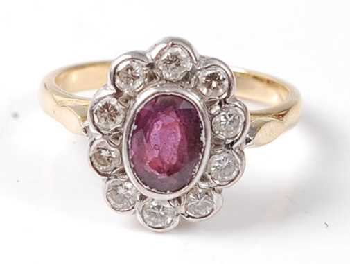 A yellow and white metal, ruby and diamond oval cluster ring, featuring a centre oval faceted ruby