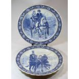 A pair of Dutch Delft style chargers, each decorated with coaching scenes, dia.42cm