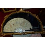 Mother-of-pearl and painted silk dress fan (a/f) housed in a gilt composition glazed frame (frame