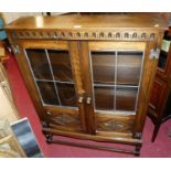 A contemporary oak double door glazed bookcase, having floral relief lower panels, w.81cm