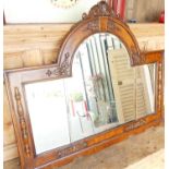 An early 20th century oak and burr oak arch top over mantel mirror, with raised floral decoration,
