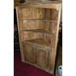 A pine freestanding corner cupboard, the panelled back with twin shaped integral open shelves over