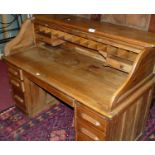 An early 20th century oak roll top kneehole writing desk, the tambour opening to reveal a pigeon