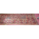 A large Persian woollen red ground Bokhara rug, having all over floral stylised ground (with fading,