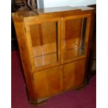 An Art Deco figured walnut side cabinet, having twin glazed upper doors over twin panelled lower