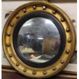 A gilt framed and ball applied convex wall mirror with eagle pediment and carved apron (pediment and