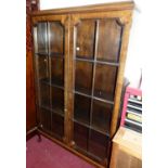 An early 20th century walnut double door glazed freestanding bookcase, raised on squat cabriole