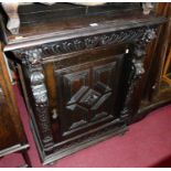 A circa 1900 geometric moulded and relief carved oak single door side cupboard, having single frieze