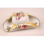 A late 19th century enamel patch box in the form of a tricorn hat, the white ground decorated with