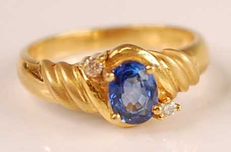 An 18ct gold Ceylon sapphire and diamond set ring, the four claw set oval cut sapphire weighing