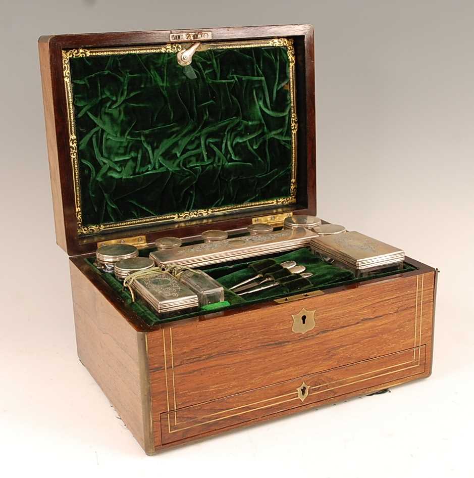 A Victorian rosewood and brass bound fitted toilet box, the hinge cover opening to reveal velvet