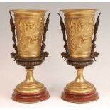 A pair of circa 1900 bronze and gilt bronze pedestal urns, each with cast leaf and flower