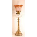 A late Victorian pedestal oil lamp, having a sepia tinted acid etched shade over a cut clear glass