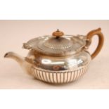 A George III silver teapot, of half-reeded circular squat form, having bright cut engraved armorial,