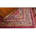 A Persian woollen Tabriz rug, having a red ground decorated with a geometric motif within trailing