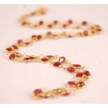 A contemporary yellow metal and ruby necklace, arranged as 50 round cut rubies, each weighing approx