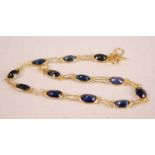 A contemporary yellow metal and sapphire set bracelet, arranged as twelve oval cut sapphires each