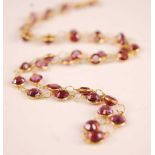 A contemporary yellow metal and rose garnet necklace, arranged as 41 round cut garnets with fine