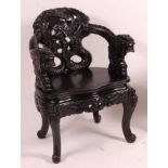 A late 19th century Chinese stained and heavily carved tub elbow chair, having Fo Dog arm terminals,