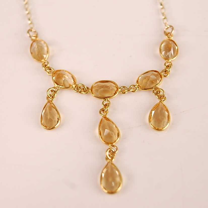 A contemporary 9ct gold citrine set necklet, arranged as nine oval cut citrine, each weighing approx