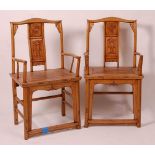 A pair of Chinese 'elm' elbow chairs, having carved splat yoke backs