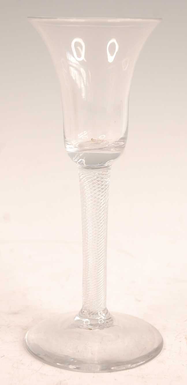 A mid-18th century wine glass, the waisted bell bowl over clear glass spiral twist column to a