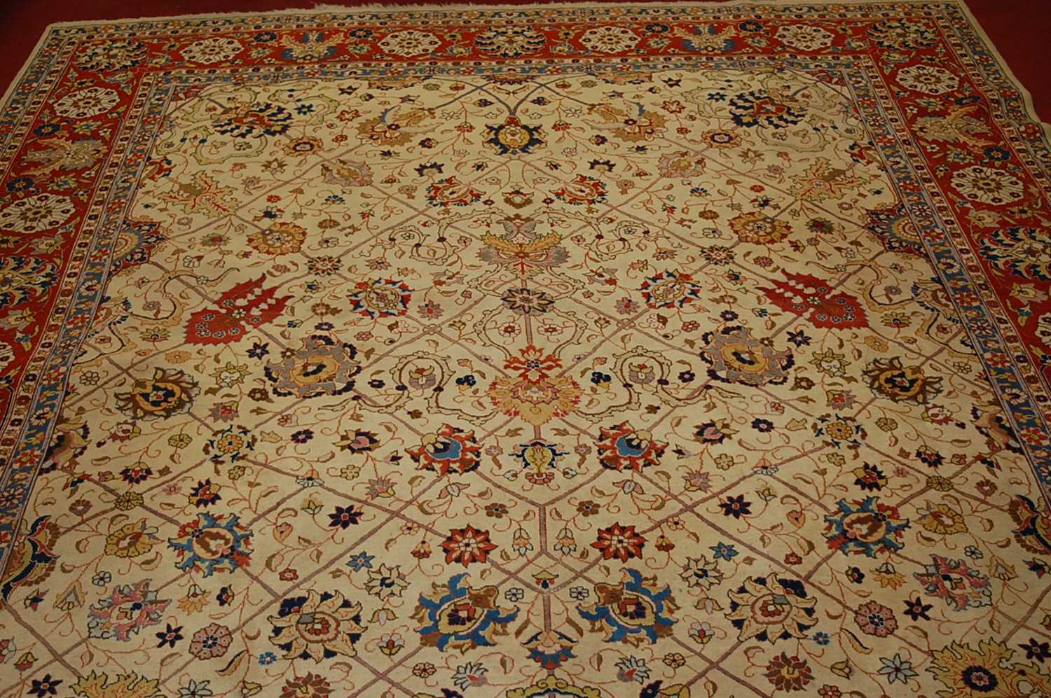 A Persian woollen cream ground carpet, decorated with scroll flowers and foliage within trailing - Image 2 of 24