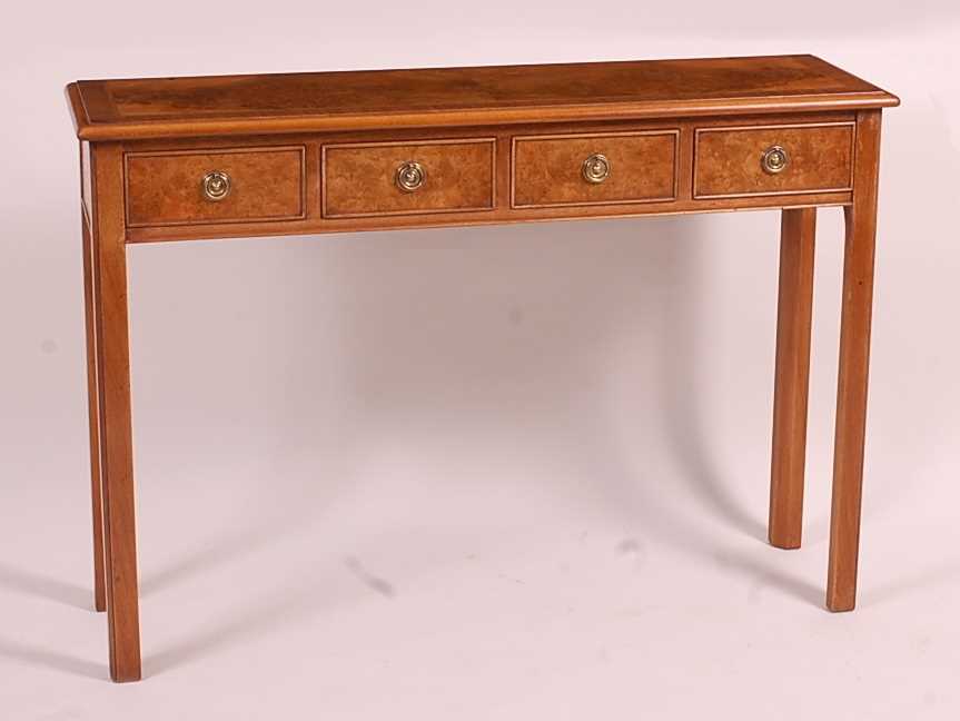 A walnut and burr walnut four drawer hall table, having a cross and feather banded top, raised on