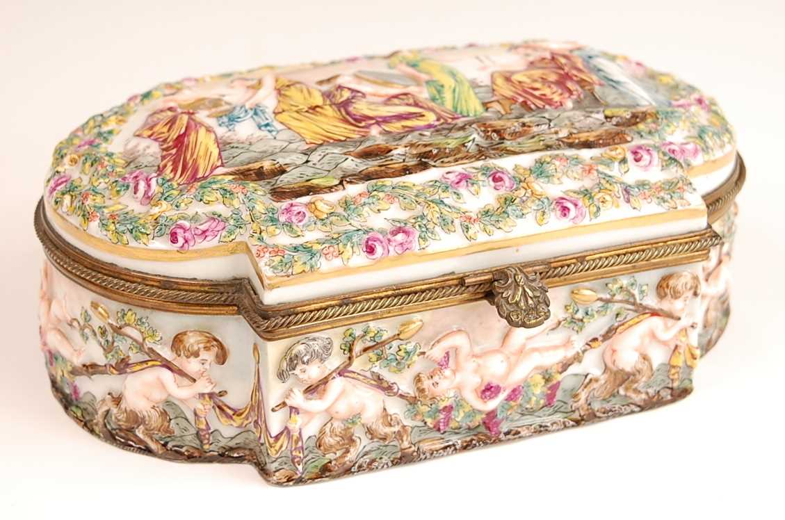 A Naples porcelain casket, having hinged cover and gilt brass mounts, the cover relief decorated