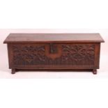 An antique joined and heavy planked oak blanket chest, having Gothic Revival relief carved front