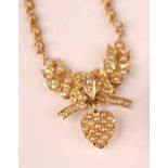 A yellow metal sweetheart necklet, comprising a central leaf and bow shaped section with a heart