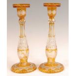 A pair of Bohemian cut and amber flash glass candle-holders, each further acid etched with