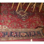 A Persian woollen Kashan carpet, having a red ground with a central medallion issuing scroll flowers