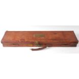 An early 20th century brown leather shotgun case, the lid with a brass plaque initialled A.D.B.H.,