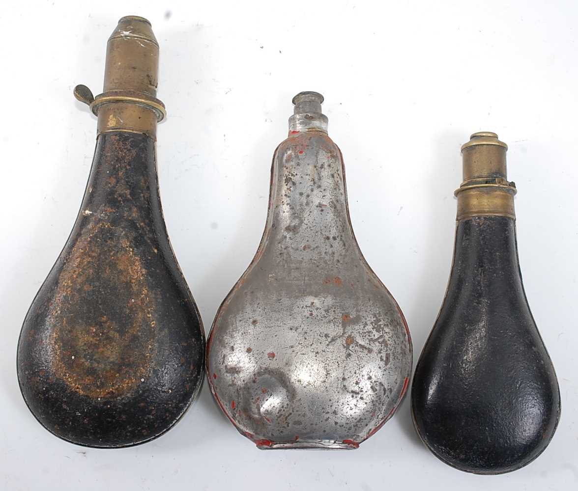 A late 19th century black painted metal powder flask of typical bag shape, the brass nozzle