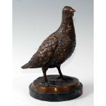 A contemporary bronzed model of a partridge in standing pose, on a naturalistic base and marble