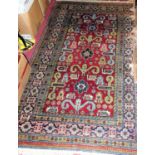 A Persian woollen red ground Shiraz rug, the geometric floral decorated central ground within
