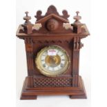 An early 20th century carved walnut cased eight-day mantel clock, the enamelled chapter ring showing