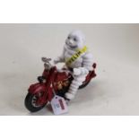 A cast iron model of the Michelin Man riding a motorcycle, h.16cm