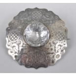 A white metal large circular Celtic brooch, engraved with scrollwork and chequerboard pattern,