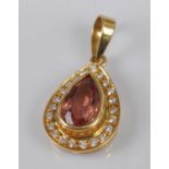 A yellow metal, topaz and diamond pear-shaped cluster pendant, featuring a centre pear cut pink