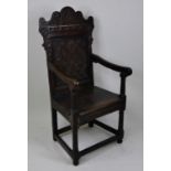 An early 18th century joined oak Wainscot chair, having a one-piece leaf and flowerhead carved