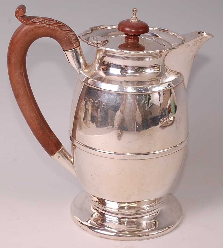 A George V silver hot water pot, of plain banded baluster form to a circular footrim, the flat