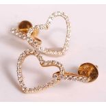 A pair of yellow metal diamond set open heart shaped drop earrings, each suspended from a bar and