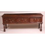 An early 18th century oak dresser base, having a two plank top over three geometric moulded frieze