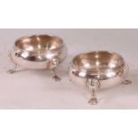 A pair of George III silver table salts, of plain bellied form with banded rims and each raised upon
