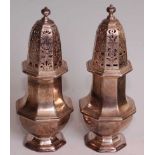 A pair of Edwardian Britannia silver sugar castors in the George II style, the bodies of plain